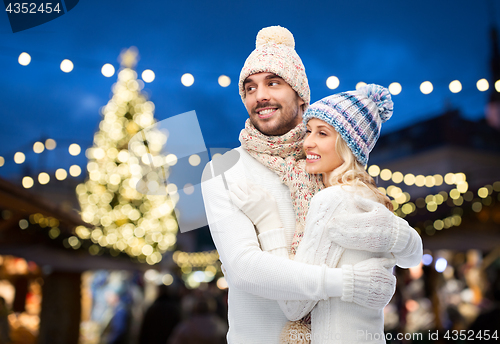 Image of happy couple hugging over christmas tree lights