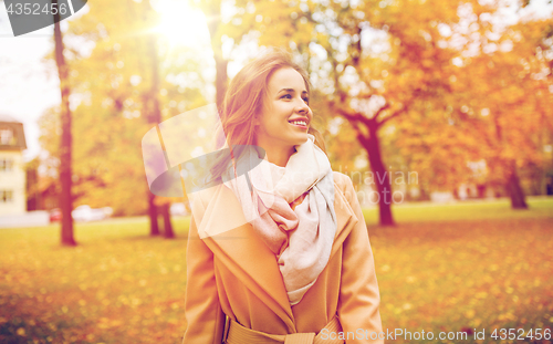 Image of beautiful happy young woman walking in autumn park