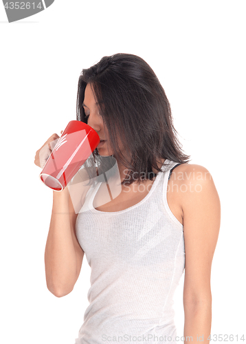 Image of Hispanic woman drinking from a red mug.