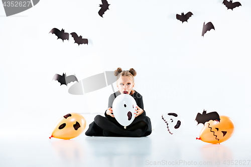 Image of Little girl witch in black dress over magical accessories. Halloween, the studio evening.