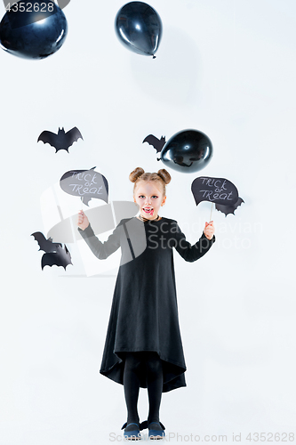 Image of Little girl witch in black dress over magical accessories. Halloween, the studio evening.