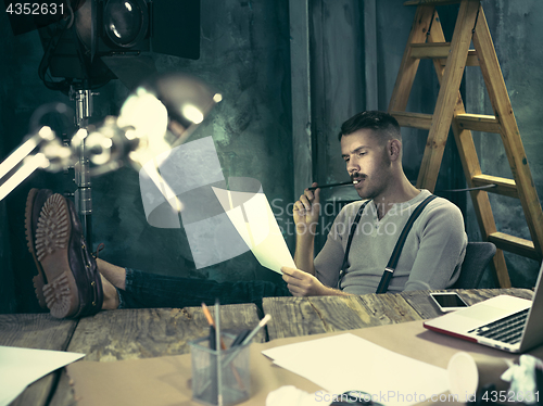 Image of Portrait of a bearded businessman who is working with his notebook at loft studio.