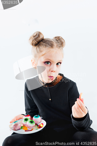 Image of Little girl witch in black dress over magical accessories. Halloween, the studio evening.