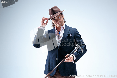 Image of The mature man in a suit and hat holding cane.