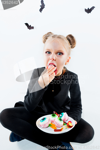 Image of Little girl witch in black dress over magical accessories. Halloween, the studio evening.