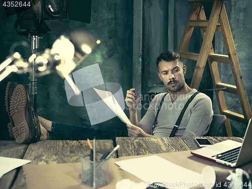 Image of Portrait of a bearded businessman who is working with his notebook at loft studio.