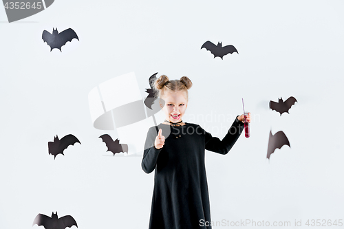 Image of Little girl witch in black dress over magical accessories. Halloween, the studio evening.