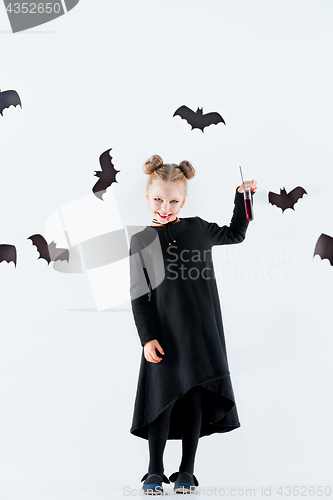 Image of Little girl witch in black dress over magical accessories. Halloween, the studio evening.