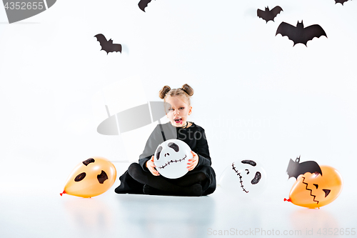 Image of Little girl witch in black dress over magical accessories. Halloween, the studio evening.