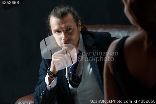 Image of The artist or mature man wearing suit in a classical retro fashion style. The woman standing near