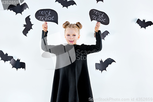 Image of Little girl witch in black dress over magical accessories. Halloween, the studio evening.