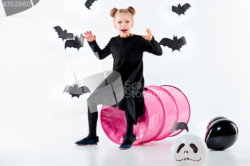 Image of Little girl witch in black dress over magical accessories. Halloween, the studio evening.