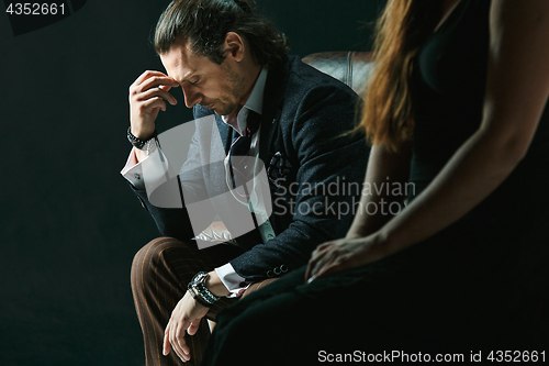 Image of The artist or mature man wearing suit in a classical retro fashion style. The woman standing near