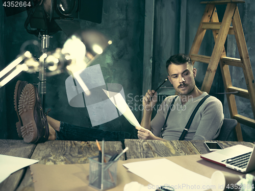 Image of Portrait of a bearded businessman who is working with his notebook at loft studio.