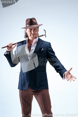 Image of The mature man in a suit and hat holding cane.