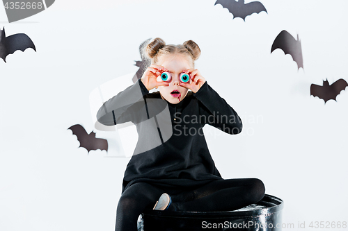 Image of Little girl witch in black dress over magical accessories. Halloween, the studio evening.