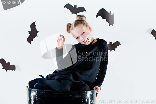 Image of Little girl witch in black dress over magical accessories. Halloween, the studio evening.