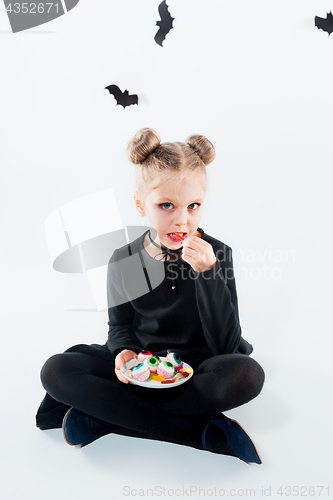 Image of Little girl witch in black dress over magical accessories. Halloween, the studio evening.