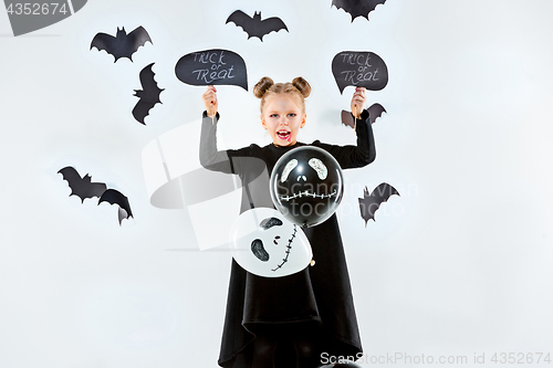 Image of Little girl witch in black dress over magical accessories. Halloween, the studio evening.