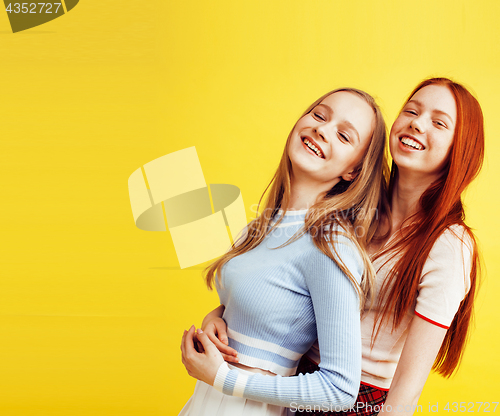 Image of lifestyle people concept: two pretty young school teenage girls having fun happy smiling on yellow background 