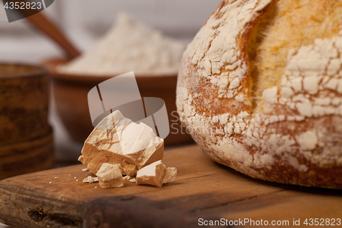 Image of Homemade bread on old cutting board with a pile of fresh yeast