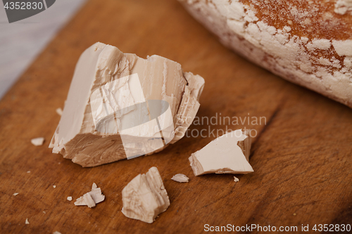 Image of A pile of fresh yeast with a Homemade bread on old cutting board