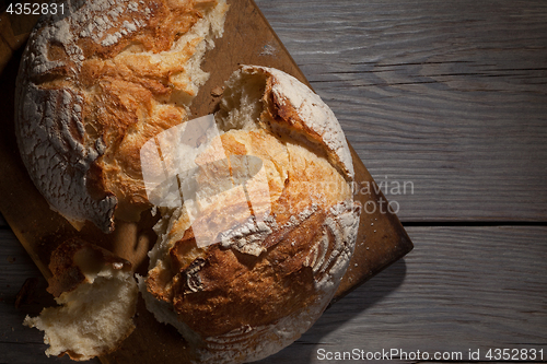 Image of Torned homemade bread loaf on old cutting board with a free space on the right