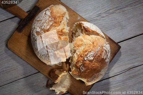 Image of Torned homemade bread loaf on old cutting board with a free space on the right