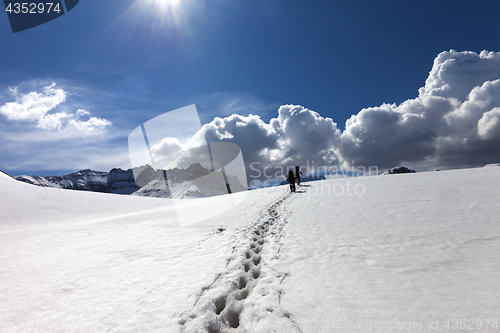 Image of Footpath in snow and two hikers on snowy plateau at sun spring d