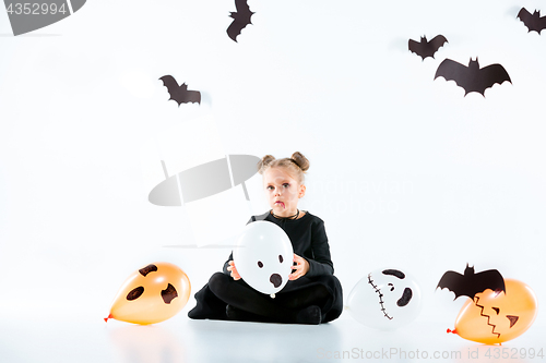 Image of Little girl witch in black dress over magical accessories. Halloween, the studio evening.