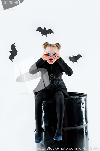 Image of Little girl witch in black dress over magical accessories. Halloween, the studio evening.