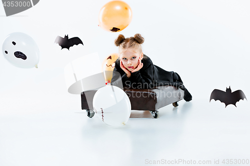 Image of Little girl witch in black dress over magical accessories. Halloween, the studio evening.