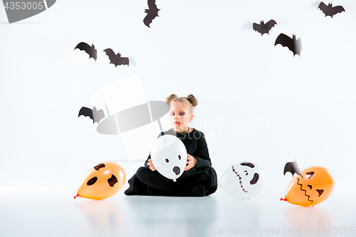 Image of Little girl witch in black dress over magical accessories. Halloween, the studio evening.