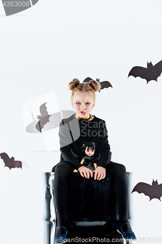 Image of Little girl witch in black dress over magical accessories. Halloween, the studio evening.