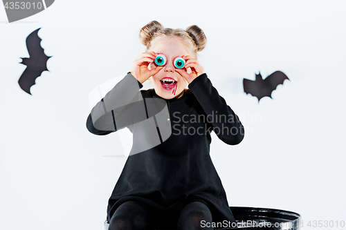 Image of Little girl witch in black dress over magical accessories. Halloween, the studio evening.