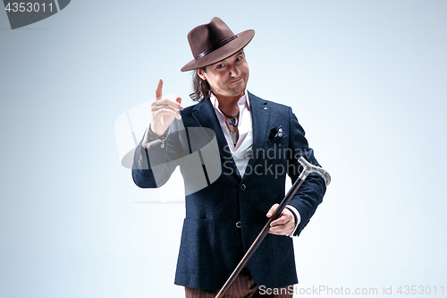 Image of The mature man in a suit and hat holding cane.