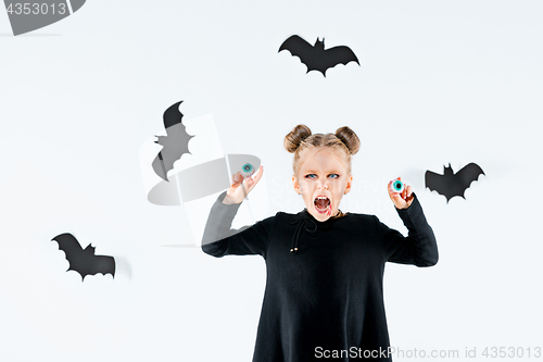 Image of Little girl witch in black dress over magical accessories. Halloween, the studio evening.