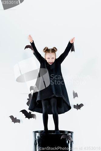 Image of Little girl witch in black dress over magical accessories. Halloween, the studio evening.