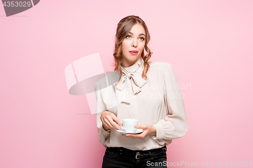 Image of The serious frustrated young beautiful business woman on pink background