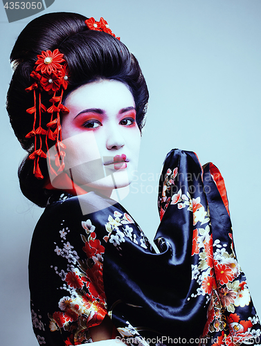 Image of young pretty geisha in kimono with sakura and red decoration des