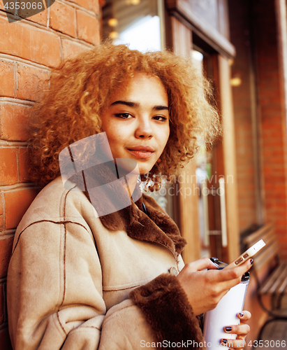 Image of young pretty african american women drinking coffee outside in c