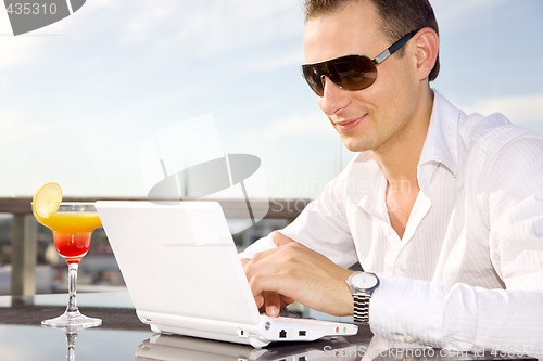 Image of businessman on leisure with laptop and cocktail