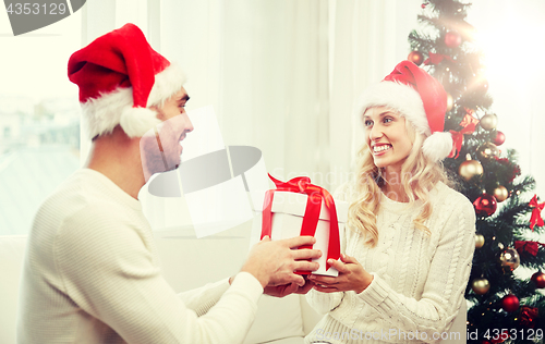 Image of happy couple at home with christmas gift box