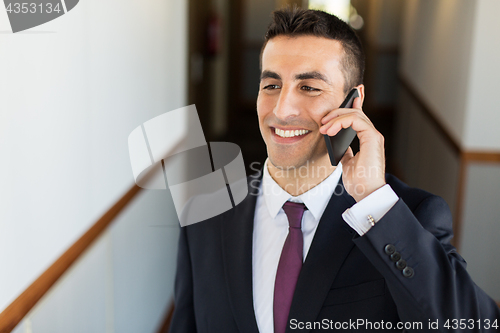 Image of smiling businessman calling on smartphone at hotel