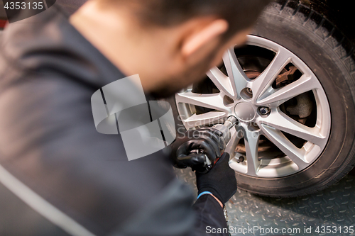 Image of auto mechanic with screwdriver changing car tire