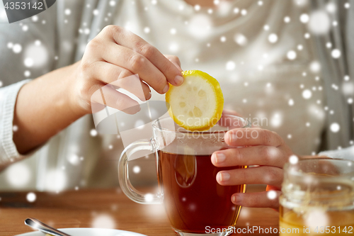 Image of close up of woman adding lemon to tea with honey