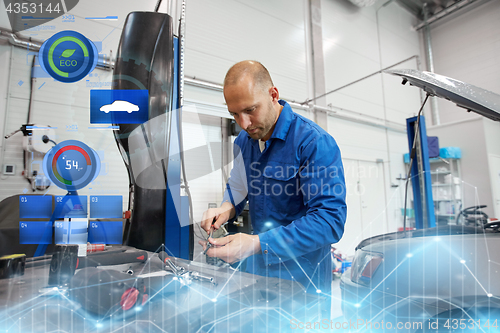 Image of mechanic man with wrench repairing car at workshop