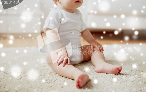 Image of happy baby boy or girl sitting on floor at home