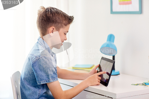 Image of smiling boy with tablet pc sitting at home desk