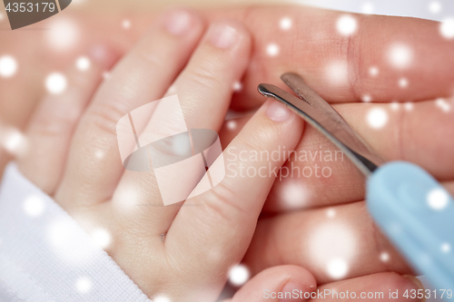 Image of close up of hand with scissors trimming baby nails